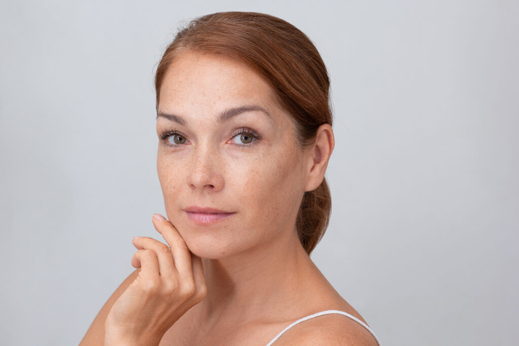 Woman looking at brown spots and melasma on her skin in Mechanicsburg, PA